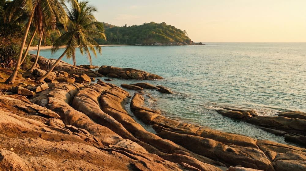 Sun-warmed reddish stone rock formation at the water edge on Koh Samui, golden hour